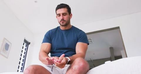 Man 30s hands together on sofa, rubbing and checking while adjusting white Stock Footage 337625281