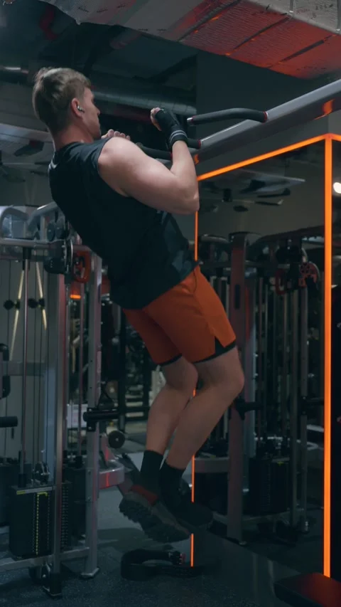 Man in 30s Performing Pull Up Back Exercise in Dark Gym Stock Footage 340550527
