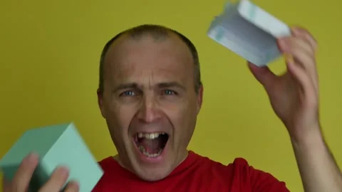 A man of 40-55 years old in a red T-shirt holds a gift box in his hand and Stock Footage 165359061