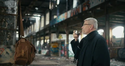 A man in an abandoned factory drinking tea from a thermos cup. Stock Footage 300802032
