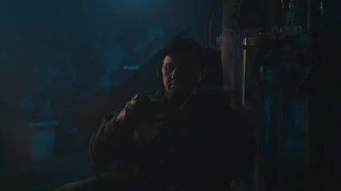 A man in an abandoned workshop sitting and smoking Vídeo Stock 258214656