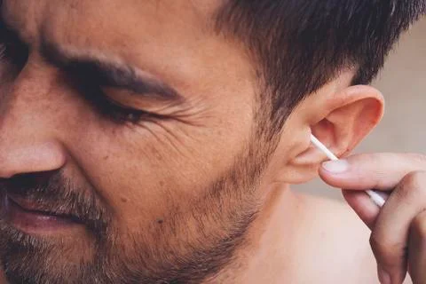 Man about to clean his ears using Q-tip cotton swab. Hygiene essentials conce Stock Photos