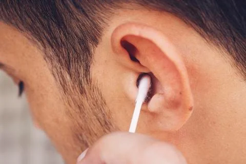 Man about to clean his ears using Q-tip cotton swab. Hygiene essentials conce Stock Photos