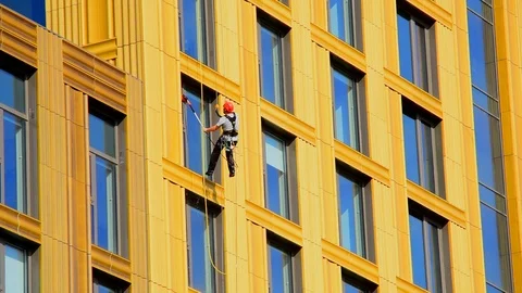 Man abseiling down building cleaning office and apartment windows uk Stock Footage 126211276