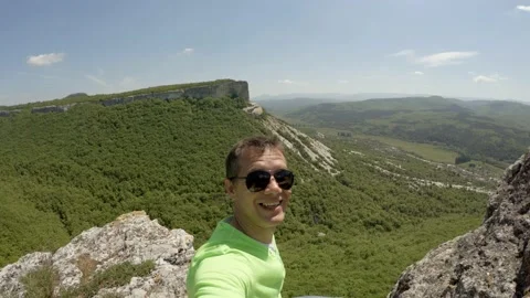 A man with an action camera sits at the very edge of the cliff. Stock Footage 95301603