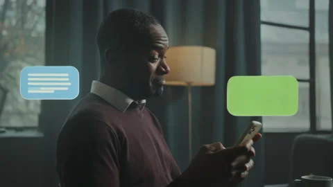 A man is actively engaged in a text conversation while in a cozy room Stock Footage 319443043