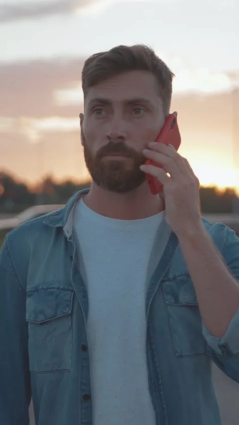 A man actively engaging in a lively conversation on his phone during a stunning 動画素材 306615918