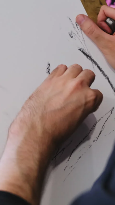 Man actively uses dark drawing tool to create marks on paper Stock Footage 316164004