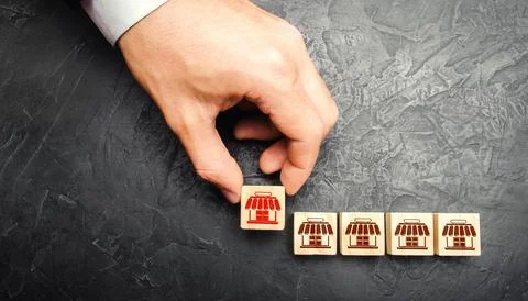 Man Adding a block with a store icon to others. Franchise commercial conces.. Stock Photos