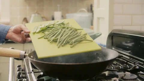Man Adding Fresh Green Beans With Spoon In Wok Stock Footage 86076686