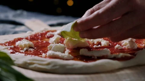Man adding fresh organic basil as topping to the pizza Video stock 132839990