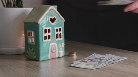 Man adding money to savings stack near house model on table Stock Footage 332723723