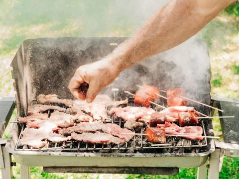 Man adding salt to barbecued meat Stock Photos