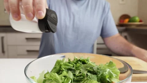 Man adding salt to vegetarian salad,kitchen, natural nutrition, meal diet Stock Footage 304137588