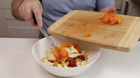 Man adding sliced ??apricot to bowl of fruit salad Stock Footage 304137766