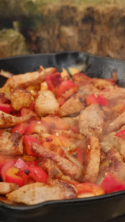Man adding spices to a steaming pan of colorful vegetables and meat Stock Footage 308718838