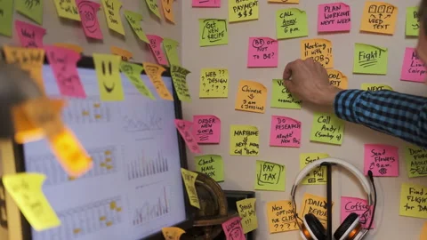 Man adding sticky notes on a wall above his desk Video stock 278824328