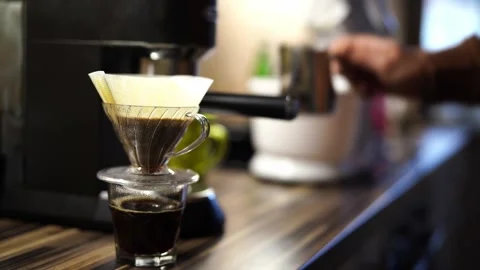 Man adding water to coffee dripping through pour over filter coffee maker Stock Footage 279859372