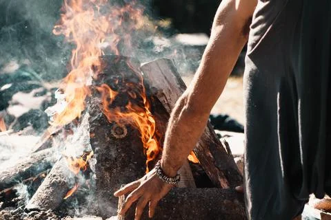 Man adding wood to campfire during camping Stock Photos