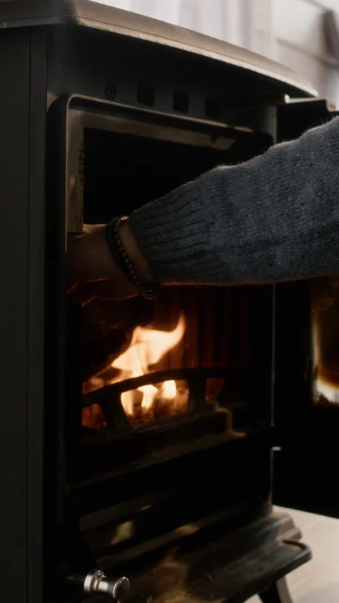 Man Adding Wood Log into Burning Cast Iron Stove for Home Heating Stock Footage 341300489