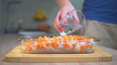 A man adds water to a dish with vegetables. Stock Footage 101554469