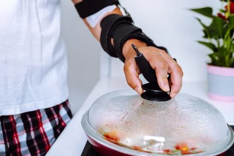 Man with adjustable elbow brace preparing food Stock Photos