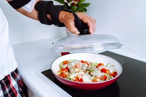 Man with adjustable elbow brace preparing food Stock Photos