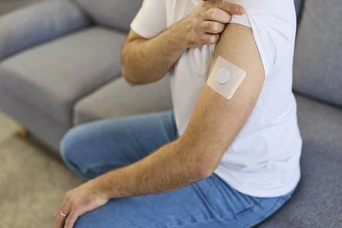 Man adjusting arm patch with glucose monitor sensor for wearable diabetes care Stock Photos