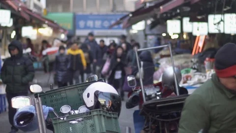 Man adjusting boxes full of stock, people walk by,Namdaemun, South Korean market 스톡 동영상 84755538