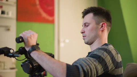 Man adjusting camera equipment, preparing for filming in creative home studio Stock Footage 317543445
