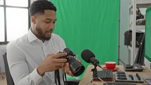 Man adjusting camera with hands at desk beside microphone and computer in s.. Stock Footage 337439887