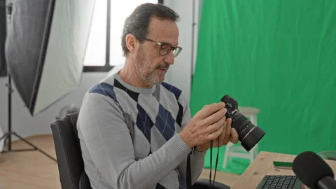 Man adjusting camera with hands while checking settings by computer at wood.. Stockbeeldmateriaal 347874198
