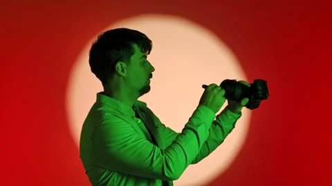 Man Adjusting Camera Lens in Artistic Lighting 库存影片 334108565
