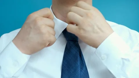 Man adjusting collar on white shirt and tie on blue background front view close Stock Footage 281037296