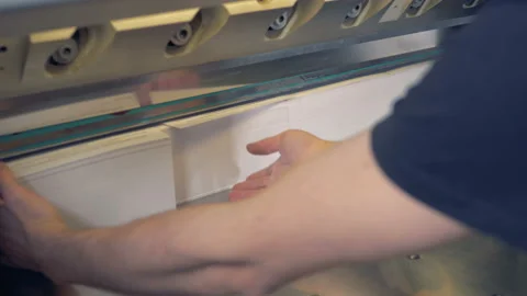 A man is adjusting four stacks of paper thereafter a cutter is shearing their Stock Footage 87251633