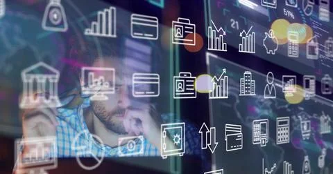Man adjusting glasses while studying monitors, charts updating as finance icons 库存照片