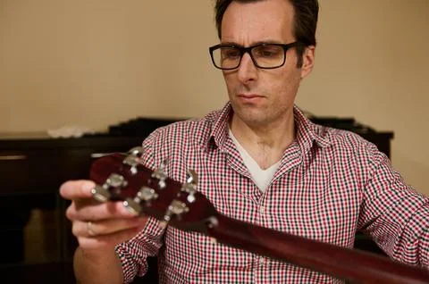 Man Adjusting Guitar Strings for Maintenance and Repair Stock Photos