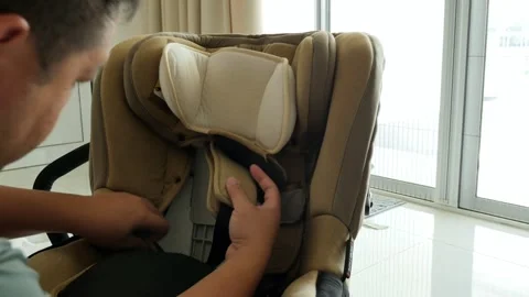 Man Adjusting Headrest and Straps on Child Car Seat by Large Window Video stock 337450220