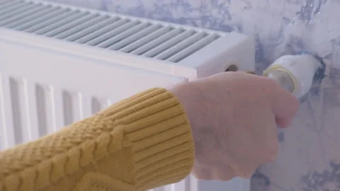 Man adjusting heating radiator or heater to install comfort temperature Stock Footage 231237078