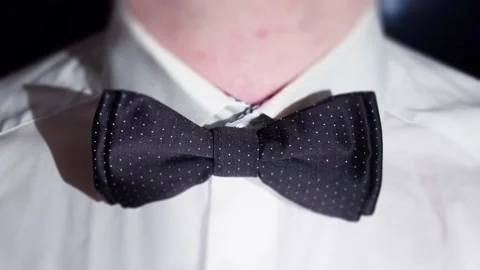Man adjusting his bow tie on a black background Video stock 233776257