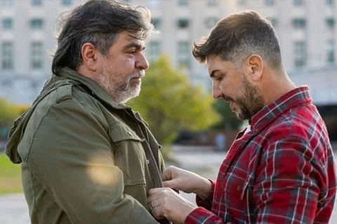 A man is adjusting his husband's jacket. Stock Photos