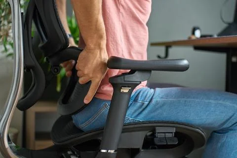 Man adjusting lumbar support on ergonomic office chair Stock-Fotos