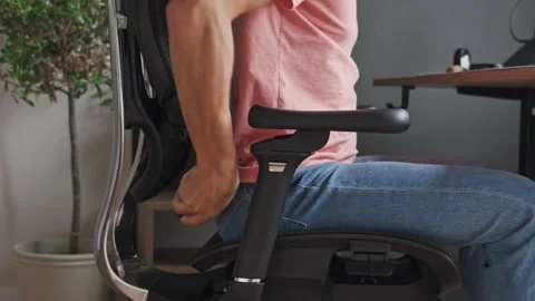 Man adjusting the lumbar support of his ergonomic chair at home Stock Footage 340490340
