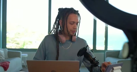 Man adjusting phone on ring light in office with ocean view, jotting notes, Stock Footage 337025699