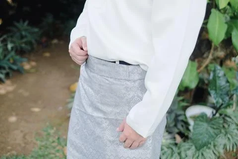 Man adjusting silver patterned traditional malay garment outdoors in daylight Stock Photos