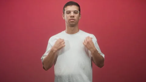 Man adjusting sleeve and touching upper arm in studio with red wall, wearin.. Stock Footage 337376524