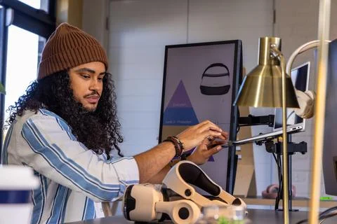 Man adjusting tablet on articulating arm at desk with headset, controllers, Stock Photos