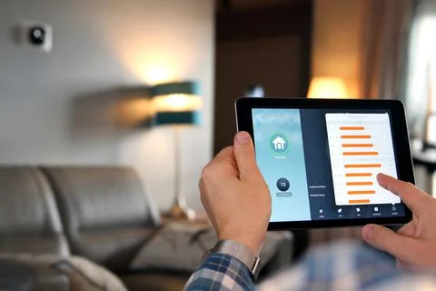 Man is Adjusting a temperature using a tablet with smart home app in room Stock Photos