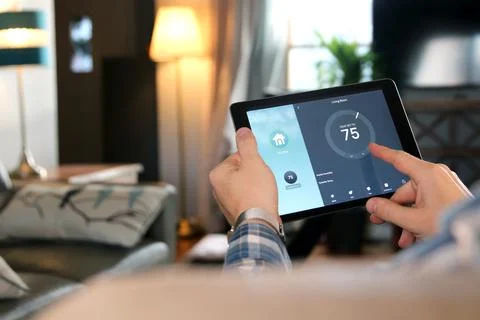 Man is Adjusting a temperature using a tablet with smart home app in room Stock Photos