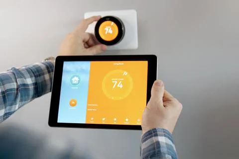 Man is Adjusting a temperature using a tablet with smart home app in room Stock Photos